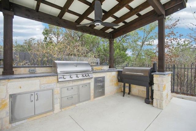 view of patio featuring ceiling fan, a grill, an outdoor kitchen, and fence