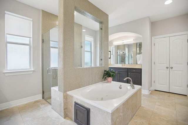 bathroom featuring a wealth of natural light, a jetted tub, a shower stall, and baseboards