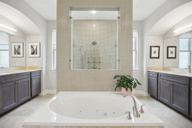 bathroom with a tub with jets, walk in shower, and a sink