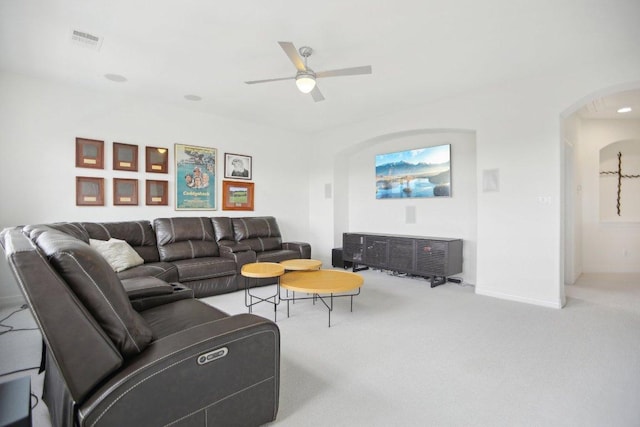 carpeted living area with a ceiling fan, arched walkways, visible vents, and baseboards