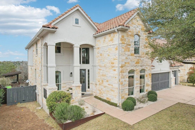 view of front facade with an attached garage, stone siding, concrete driveway, and a tiled roof