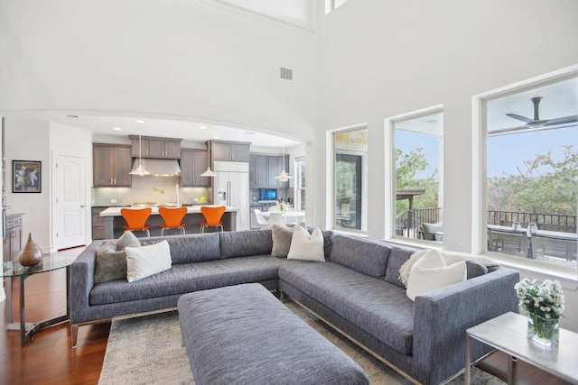 living area with ceiling fan, recessed lighting, a high ceiling, visible vents, and dark wood finished floors