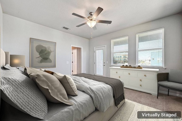 bedroom featuring light carpet, ceiling fan, visible vents, and a textured ceiling