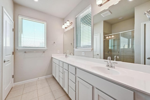 bathroom featuring double vanity, a stall shower, a sink, baseboards, and tile patterned floors