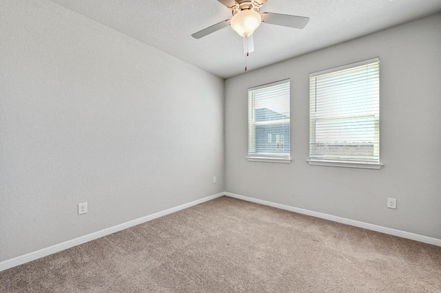 carpeted empty room with ceiling fan, a textured ceiling, and baseboards