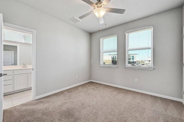 empty room featuring ceiling fan, light tile patterned floors, light carpet, visible vents, and baseboards