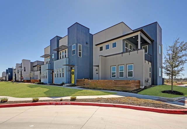 view of front facade featuring metal roof, a front lawn, a standing seam roof, and stucco siding