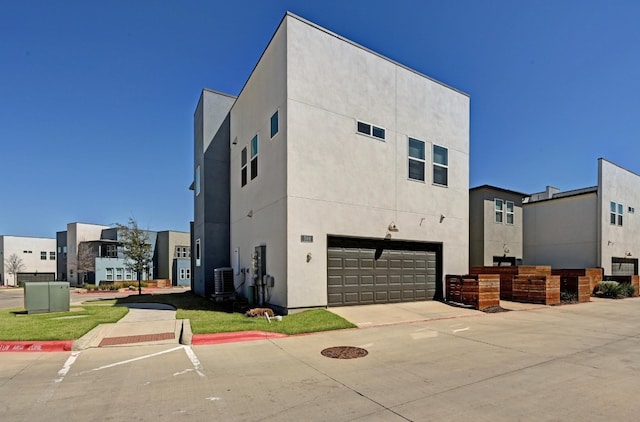 exterior space with central AC, an attached garage, and stucco siding