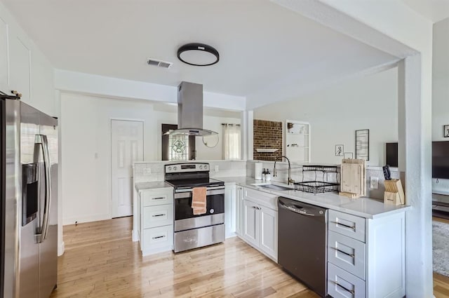 kitchen with visible vents, light wood-style flooring, island exhaust hood, stainless steel appliances, and a sink