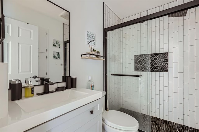 bathroom featuring toilet, a tile shower, and vanity