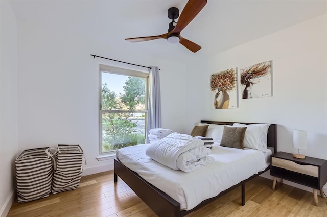 bedroom featuring light wood-style flooring, multiple windows, baseboards, and a ceiling fan