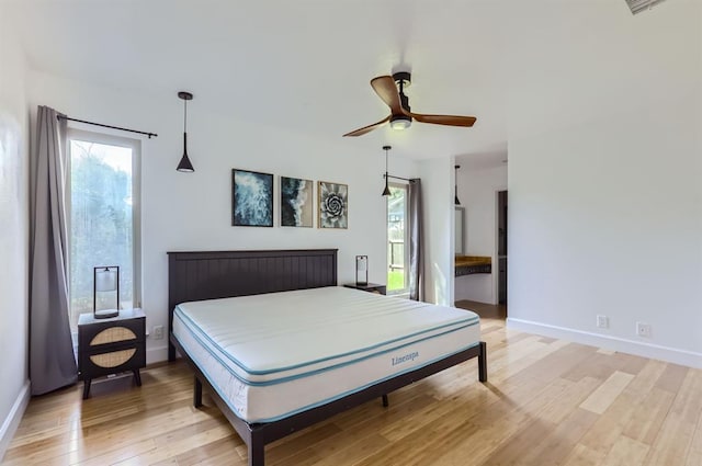 bedroom featuring baseboards, multiple windows, a ceiling fan, and light wood-style floors