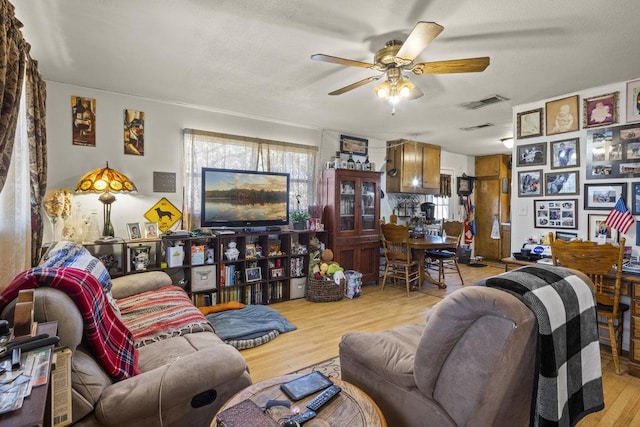 living area featuring a ceiling fan, visible vents, and wood finished floors