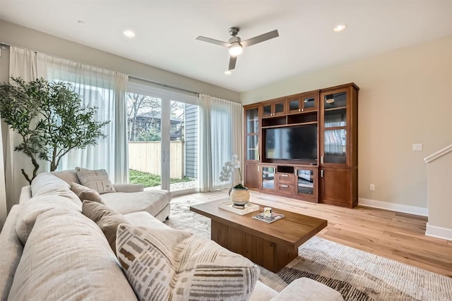 living room with recessed lighting, light wood-type flooring, a ceiling fan, and baseboards