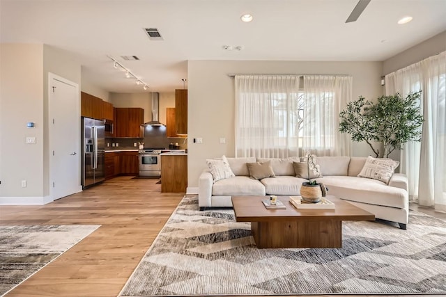 living area featuring light wood-type flooring, visible vents, rail lighting, and recessed lighting