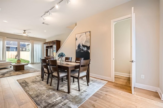 dining area featuring baseboards, visible vents, ceiling fan, rail lighting, and light wood-style floors