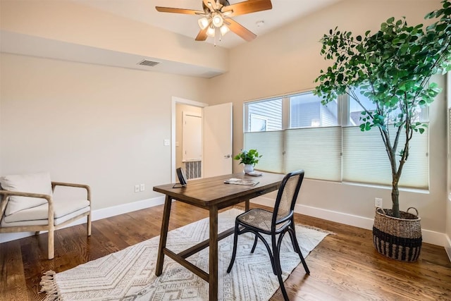 office space featuring a ceiling fan, visible vents, baseboards, and wood finished floors