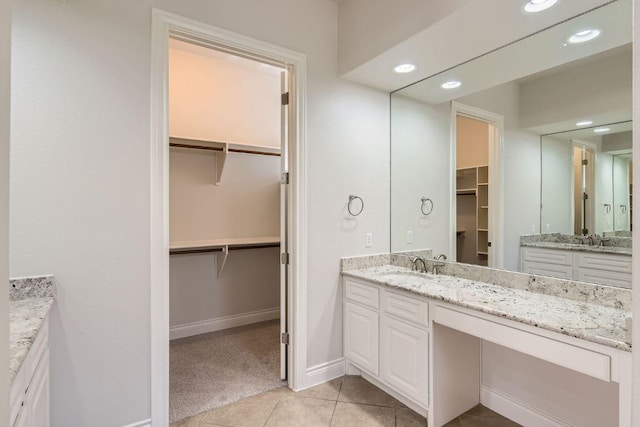 304 Belforte Ave, Austin, TX 78734 - bathroom with two vanities, a walk in closet, tile patterned floors, recessed lighting, and baseboards