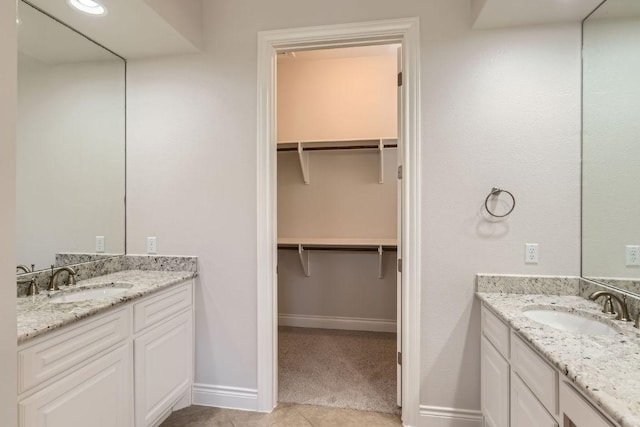 304 Belforte Ave, Austin, TX 78734 - full bathroom featuring two vanities, baseboards, a walk in closet, and tile patterned floors