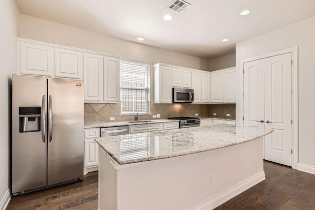 304 Belforte Ave, Austin, TX 78734 - kitchen with stainless steel appliances, white cabinetry, dark wood-type flooring, a kitchen island, and backsplash