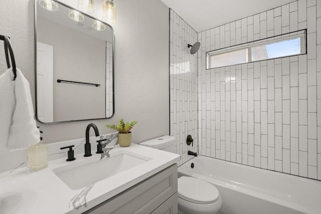 bathroom with a textured wall, bathtub / shower combination, vanity, and toilet