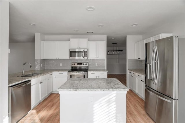 kitchen featuring stainless steel appliances, white cabinetry, a sink, and light wood finished floors