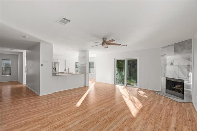 unfurnished living room with light wood-type flooring, visible vents, and a fireplace