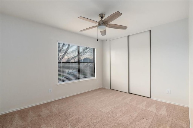 unfurnished bedroom with a ceiling fan, a closet, and light colored carpet