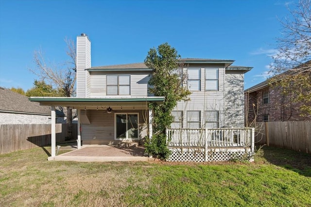 rear view of house featuring a yard, a chimney, a patio area, a deck, and a fenced backyard