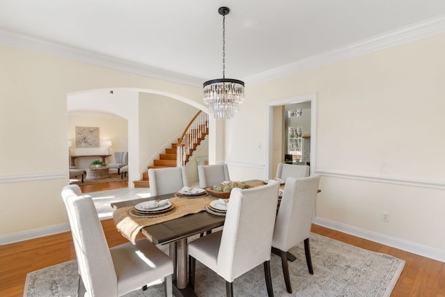 dining area with stairs, ornamental molding, light wood-style flooring, and baseboards