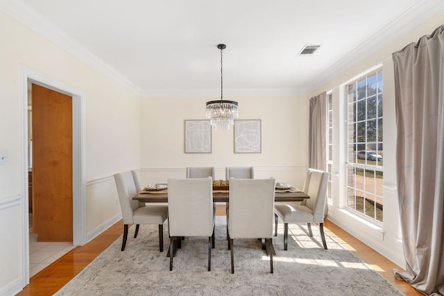 dining room with an inviting chandelier, visible vents, wood finished floors, and ornamental molding