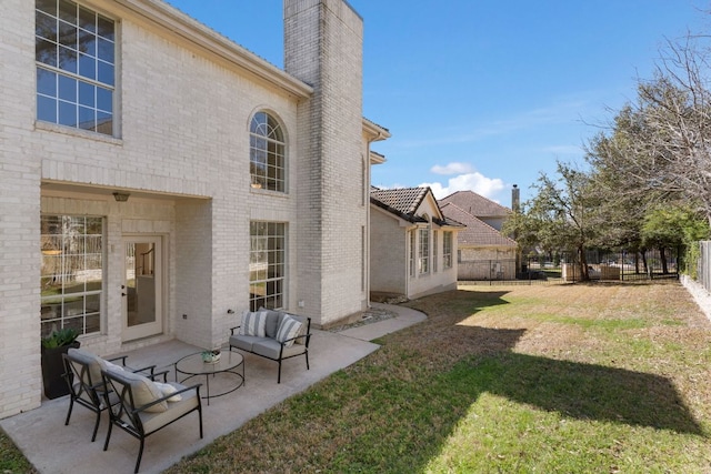 back of house featuring brick siding, a chimney, a patio area, and a lawn