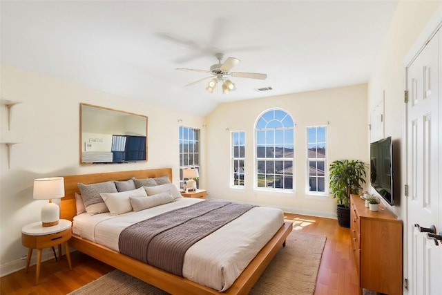 bedroom with baseboards, vaulted ceiling, visible vents, and light wood-style floors