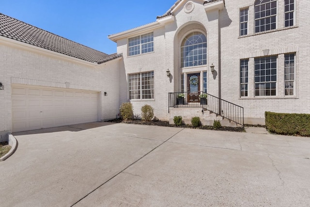 view of front facade featuring concrete driveway, brick siding, and an attached garage