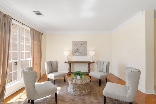 living area featuring baseboards, visible vents, crown molding, and wood finished floors