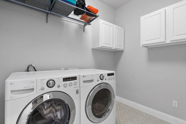 laundry area featuring washer and clothes dryer, cabinet space, and baseboards