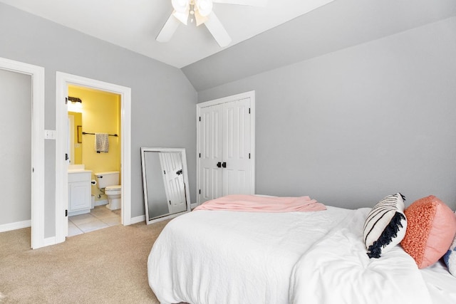 bedroom featuring lofted ceiling, ensuite bathroom, a ceiling fan, light carpet, and baseboards