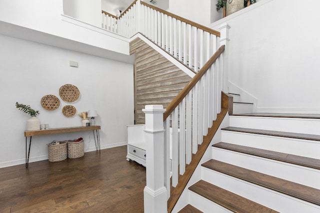 stairs featuring a towering ceiling, baseboards, and wood finished floors