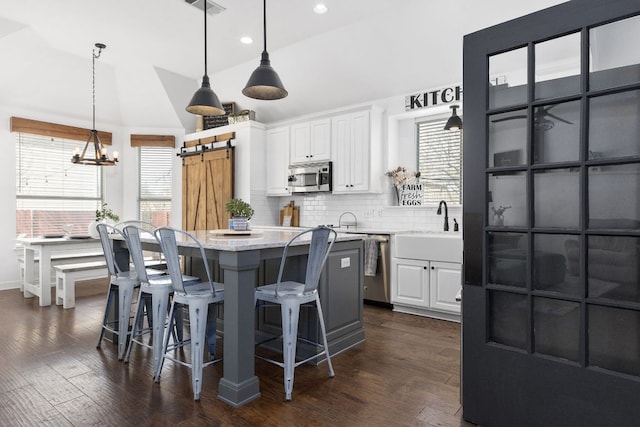 kitchen featuring stainless steel appliances, white cabinetry, a kitchen island, and a barn door