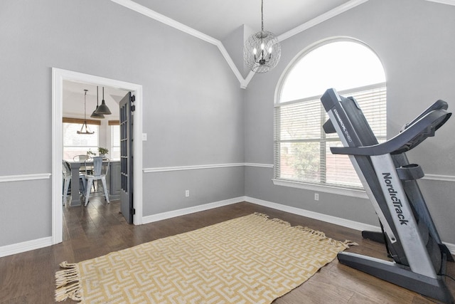 exercise room with an inviting chandelier, ornamental molding, vaulted ceiling, and wood finished floors