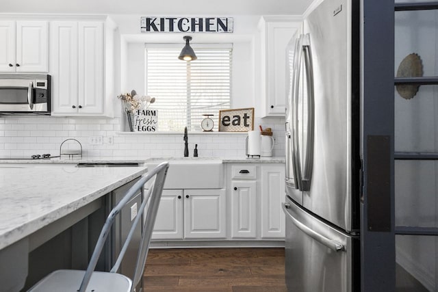 kitchen featuring decorative backsplash, dark wood-style floors, appliances with stainless steel finishes, white cabinetry, and a sink