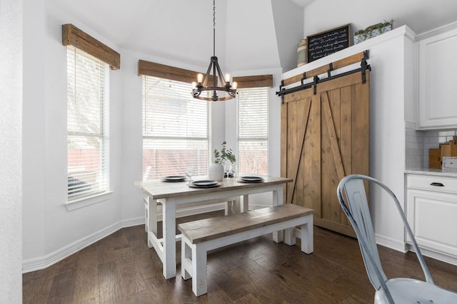 dining room with dark wood-style floors, a barn door, a notable chandelier, and baseboards