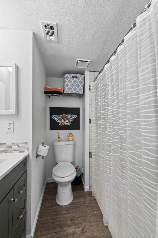 2401 Leon St Unit 208, Austin, TX 78705 - full bathroom featuring visible vents, vanity, wood finished floors, toilet, and a textured ceiling