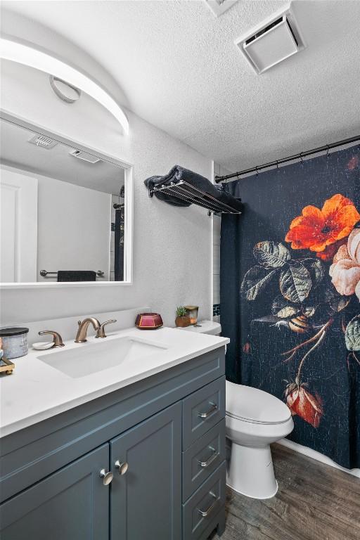 2401 Leon St Unit 208, Austin, TX 78705 - bathroom with vanity, toilet, a textured ceiling, wood finished floors, and visible vents