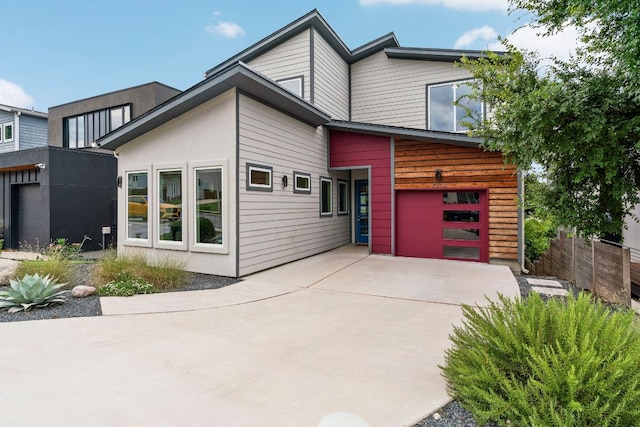 view of front of property featuring a garage, concrete driveway, and fence