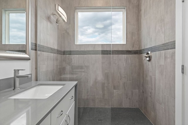 bathroom with a tile shower and vanity