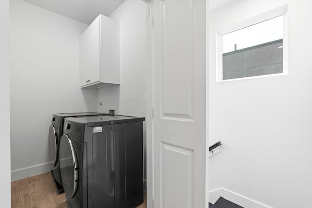 laundry room featuring light wood finished floors, washing machine and dryer, cabinet space, and baseboards