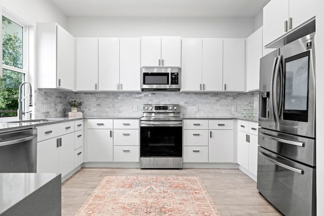 kitchen featuring stainless steel appliances, white cabinetry, a sink, and decorative backsplash