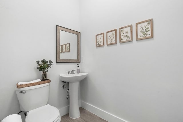 bathroom with toilet, a sink, baseboards, and wood finished floors