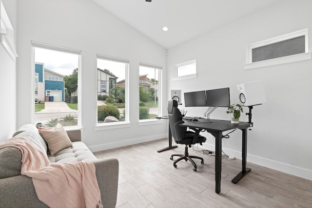 office space featuring high vaulted ceiling, light wood finished floors, and baseboards